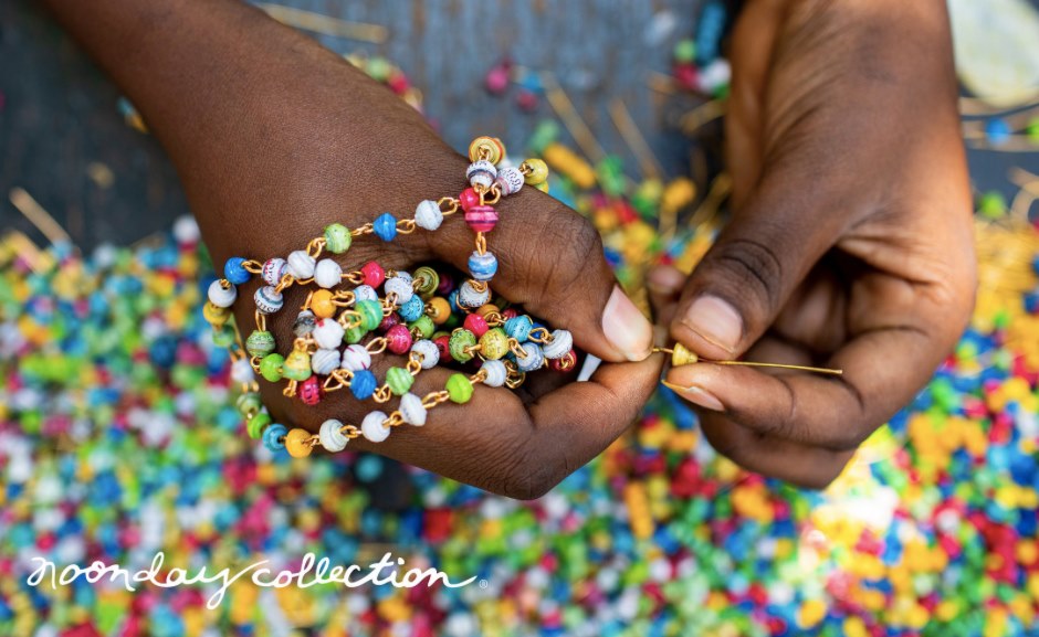 Hands stringing beads onto necklace