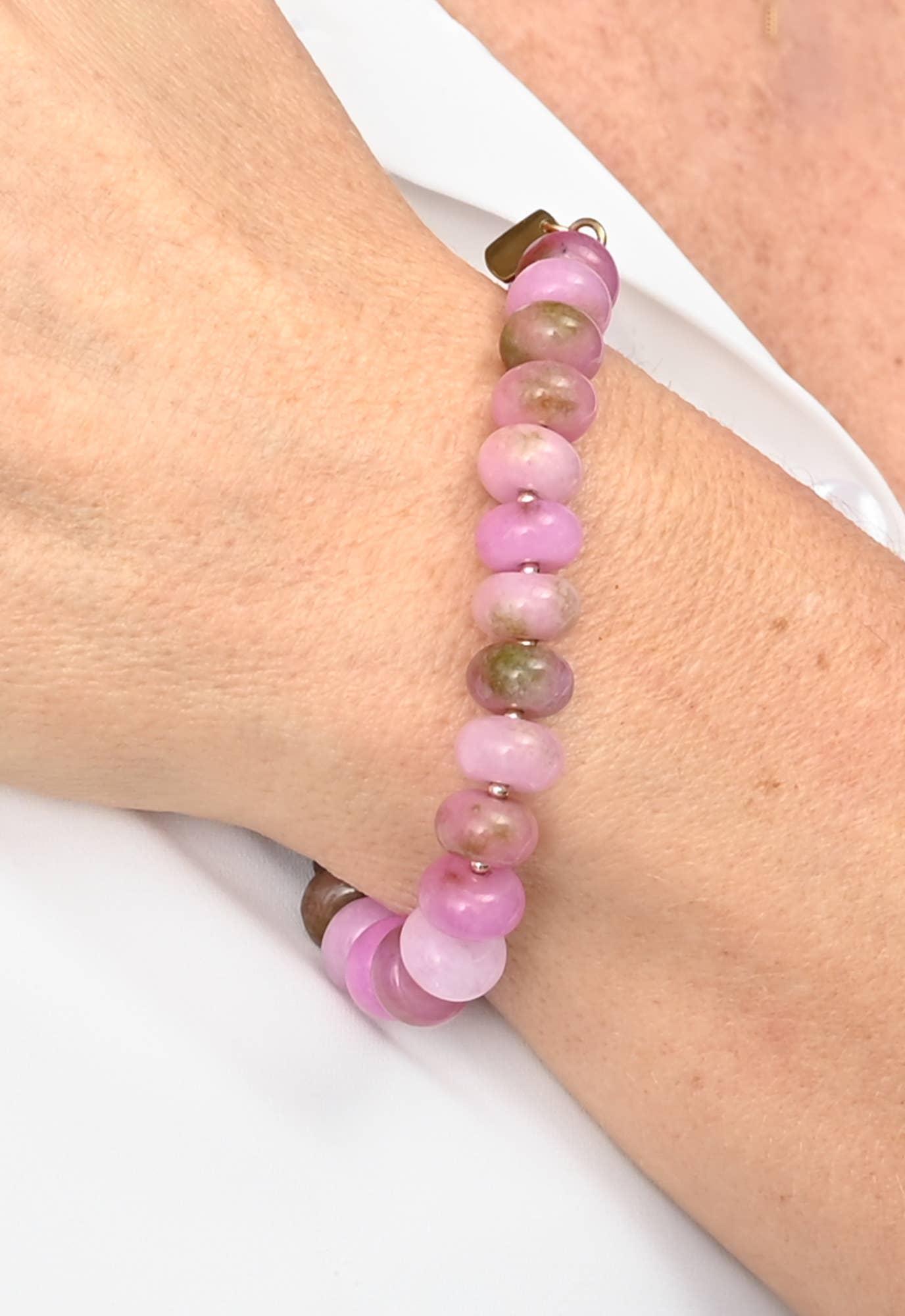 Pink beaded bracelet on a wrist with a white background