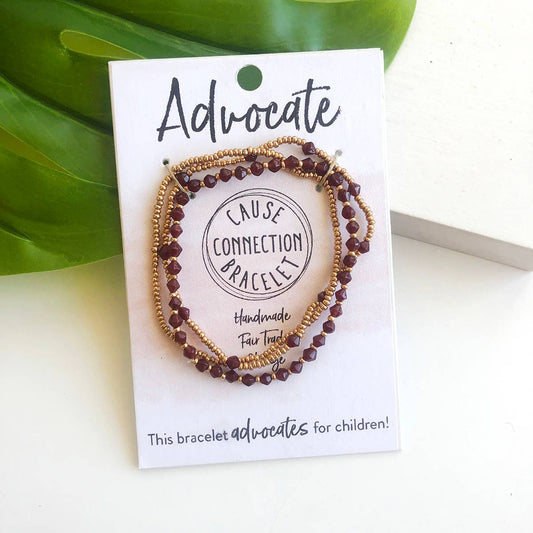 Red Advocate Cause Connection handmade beaded bracelet on a white card with green leaves, supporting relief for children.