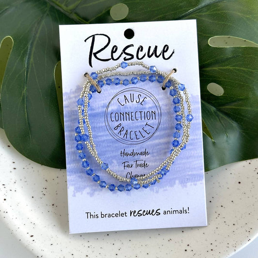 Blue beaded bracelet on a 'Rescue Cause Connection Bracelet' card with green leaves in the background