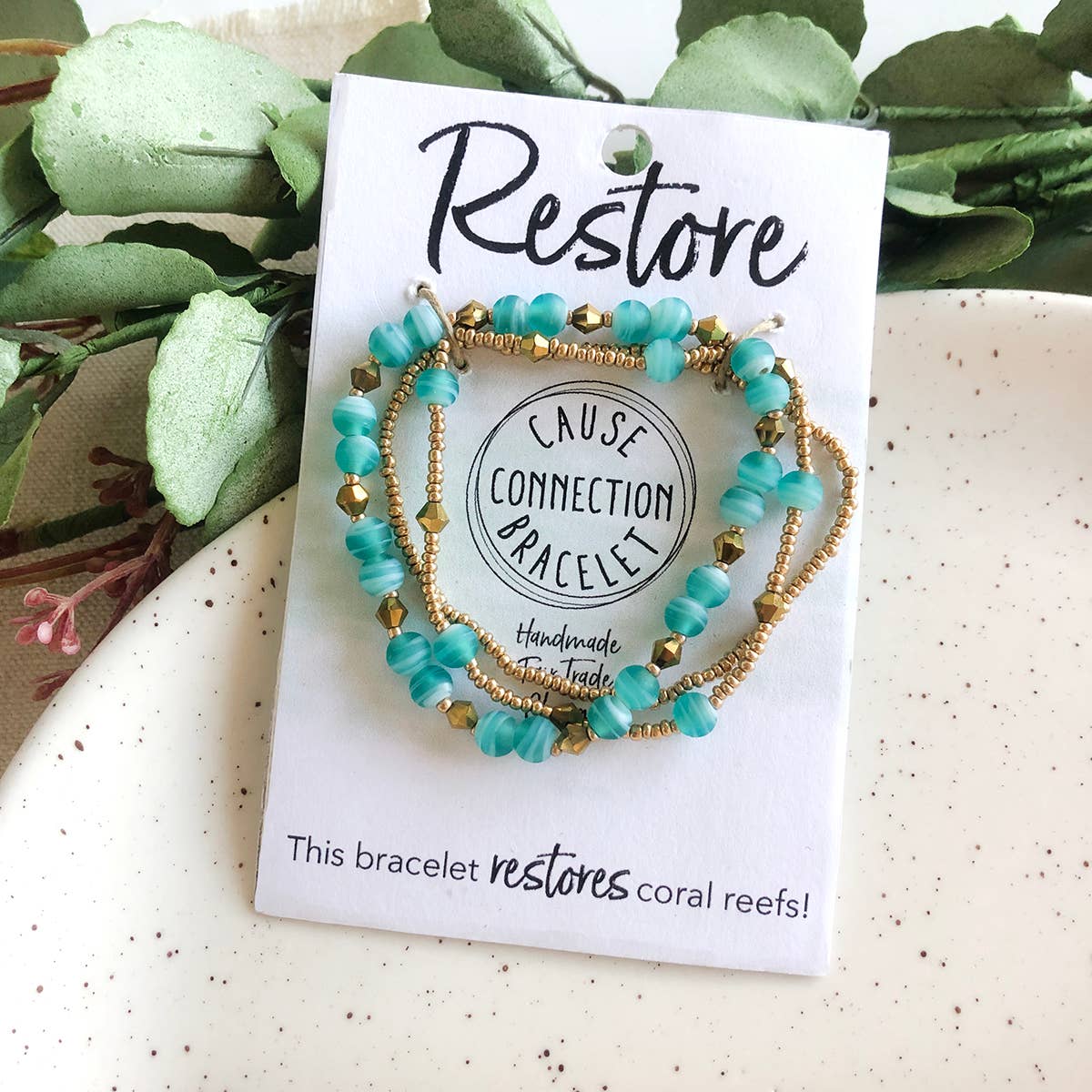 Turquoise Restore Cause Connection handmade fair trade bracelet on packaging that helps restore coral reefs and supports dignified work.